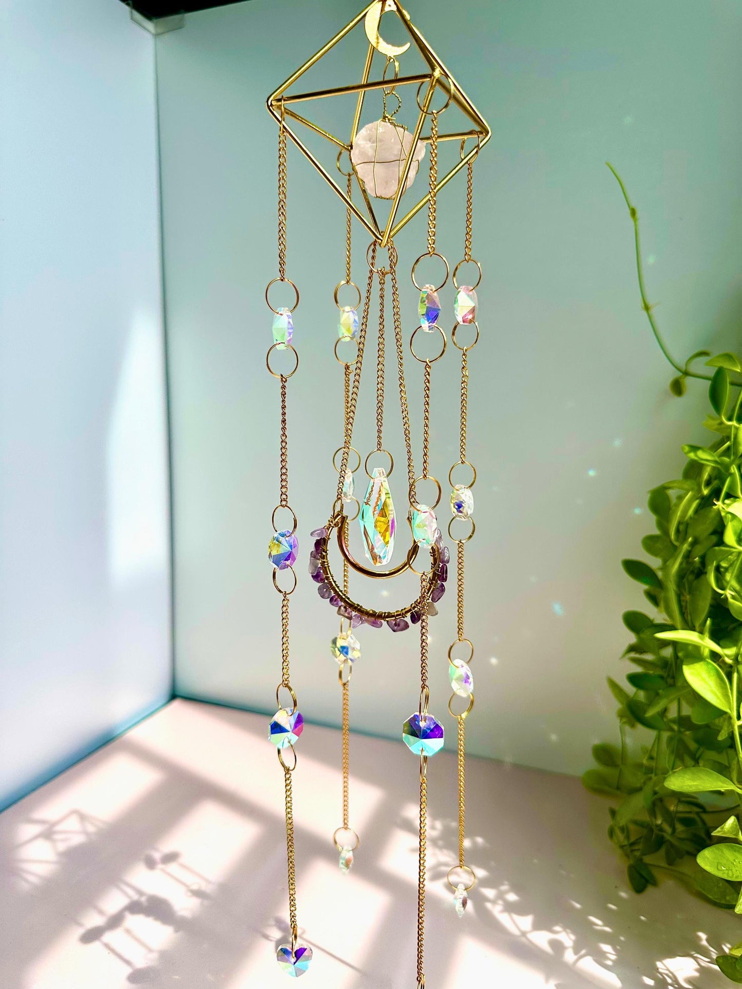 Bright window decor featuring a celestial suncatcher with prism drop and
moon pendant, glowing with pastel sparkles.